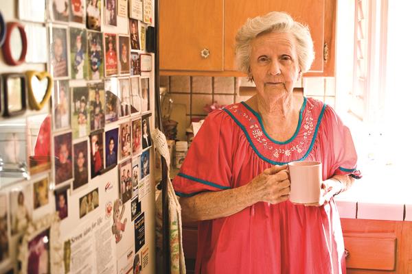 Elderly woman in her kitchen holding a cup of coffee