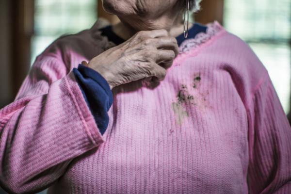 Senior woman wearing unkept pink sweater with stains on it