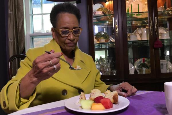 Senior woman sitting at dining room table eating healthy meal.