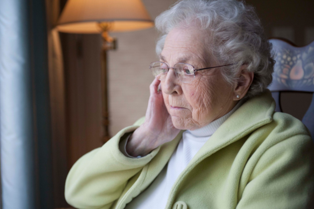 Senior woman with Alzheimer's sitting in chair at home.