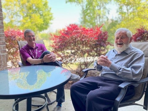 Bill and Jean Marc sitting outdoors, laughing